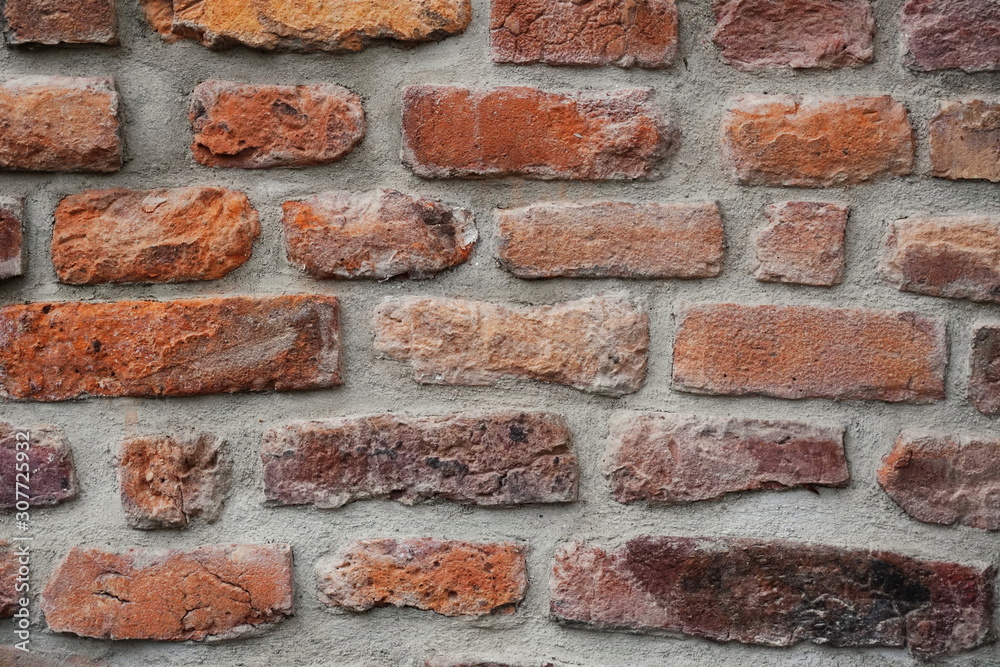 Fototapeta premium Fragment of the restoration of masonry of old red brick. different size and color bricks, background, screensaver place for text, copyspace.