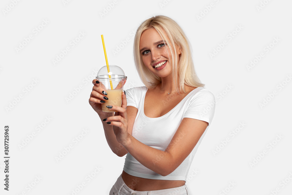 Funny cute attractive careless blonde woman is drinking cocktail in a plastic cup using a straw, isolated on white background. So delicious. Sexy smiling girl with juice. Funny cute attractive careless blonde woman is drinking cocktail in a plastic cup using a straw, isolated on white background. So delicious. Sexy smiling girl with juice.