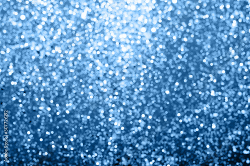 Abstract composition. Blurred photo of glitter with beautiful bokeh in classic blue, color of the year 2020. Defocused light.