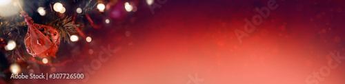 Red Christmas banner of tree decorations and glowing lights on a blurred festive background.