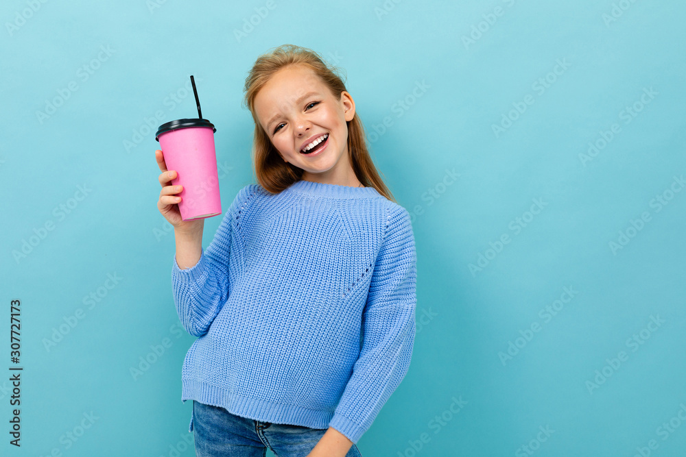 pretty european girl holding a glass in her hands on a light blue background with copyspace pretty european girl holding a glass in her hands on a light blue background with copyspace