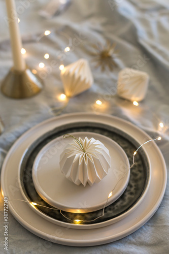 Christmas table setting with stoneware ceramic plates and origami decorations