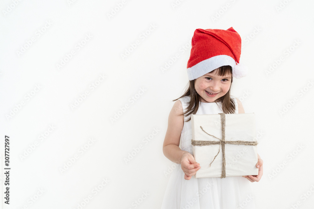 Happy girl in a red cap. The child holds a box with a gift in eco-friendly packaging. Happy girl in a red cap. The child holds a box with a gift in eco-friendly packaging.