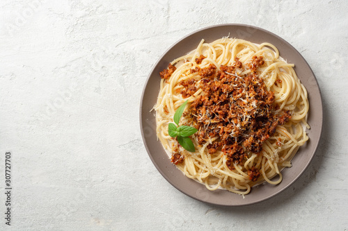 Spaghetti pasta bolognese in plate on concrete background. Top view, copy space.