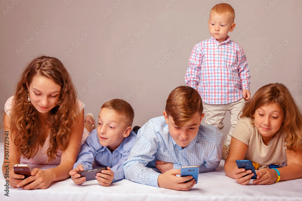 Group of little friends smiling and gaming on smart phones and mobile devices.