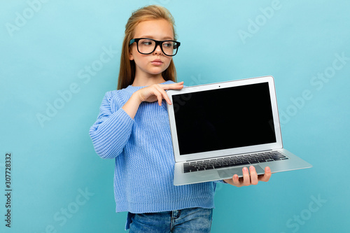 serious european girl holding a computer in her hands with the screen forward with mockupon a light blue background photo