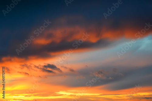 Dark thunderclouds on a golden sky during sunset. Afterglow of sunset. Scenic sundown cloudscape for background. © Maryia