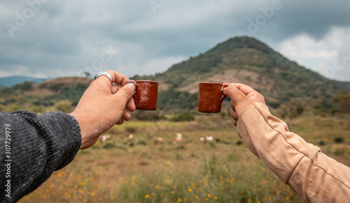 Friends enjoying a drink of mezcal, their hands say cheers in the mezcalero field photo