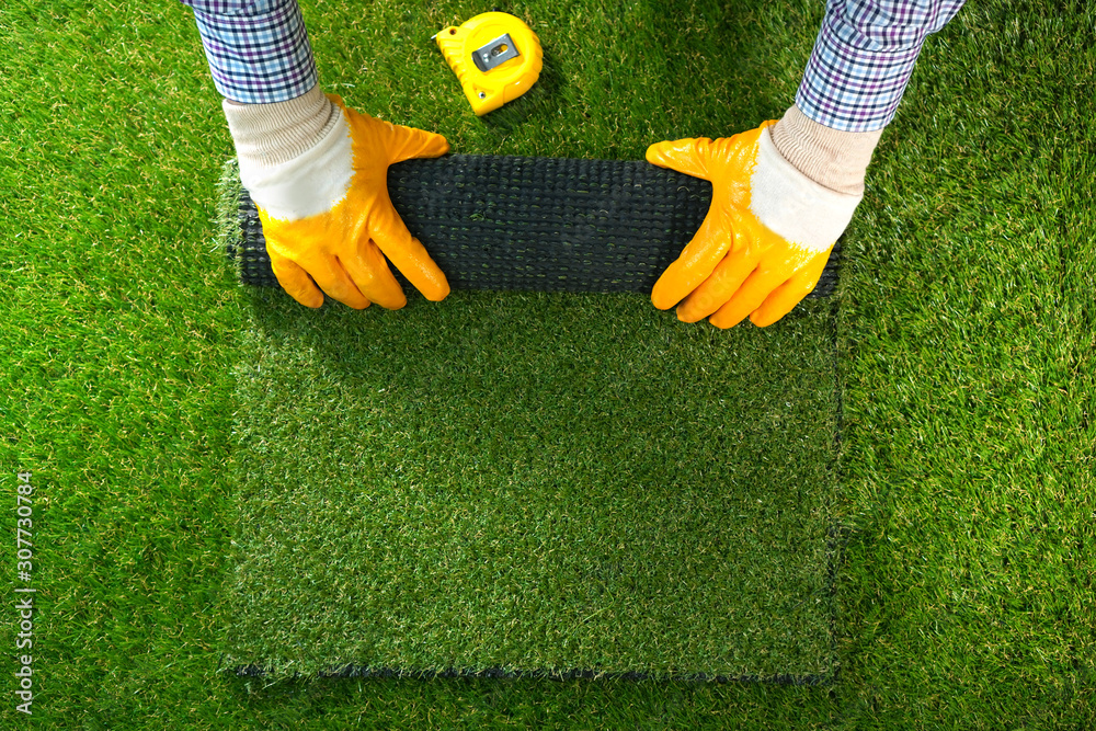 Ταπετσαρία Men's hands hold a roll of artificial grass