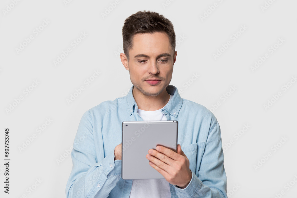 Handsome man standing scrolling and typing on electronic tablet device Handsome man standing scrolling and typing on electronic tablet device