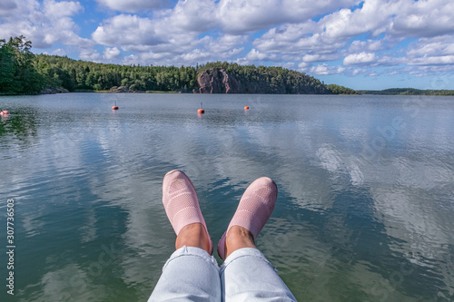 Female legs over the water. Day of rest.Summer Scandinavian landscape of the Aland Islands Midsummer day in the Åland Islands between Finland and Sweden photo