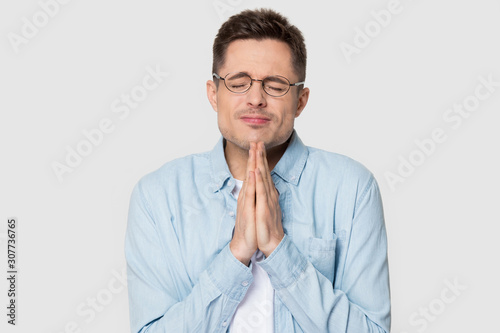 Young man begging praying with eyes closed put hands together