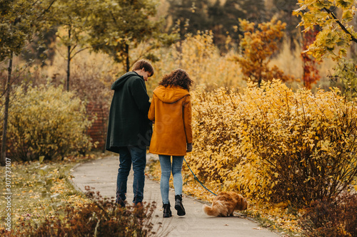 Young couple with a red cat on a background of an autumn park.