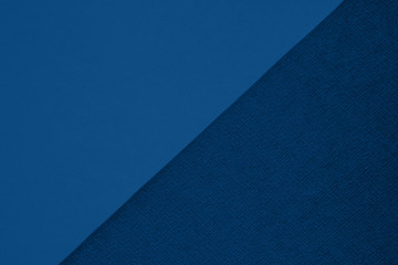 Textured and plain paper sheets divided diagonalliy creating line partition. Classic blue colored abstract duo tone background design. Copy space for text. Top view, flat lay. Color of the year 2020