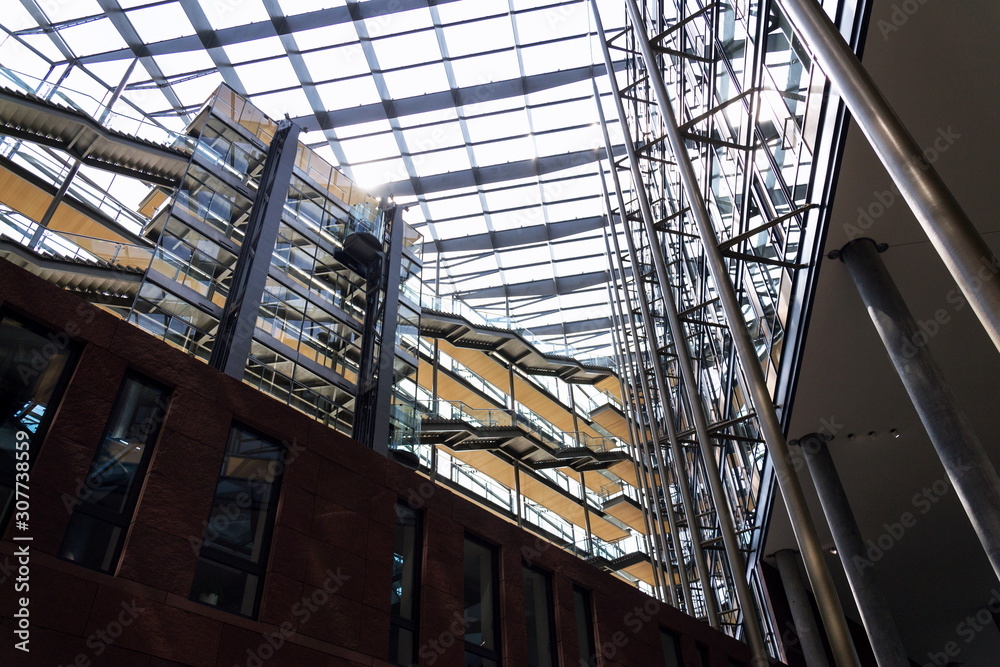 Glass lift at glazed atrium in modern office space interior, future of work, coworking, shared workplace concept Glass lift at glazed atrium in modern office space interior, future of work, coworking, shared workplace concept