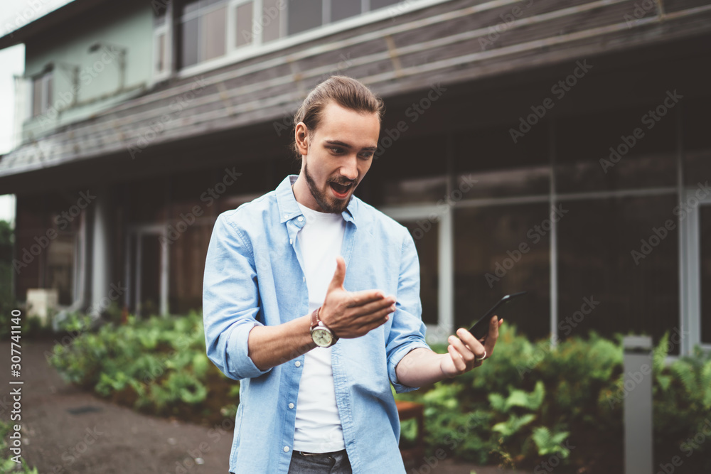 Excited man using smartphone outside house Excited man using smartphone outside house