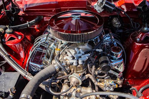 red classic muscle car under the hood, v8 engine with big chromed round air intake filter, tubes, wires, pipes, mechanical and electrical other parts
