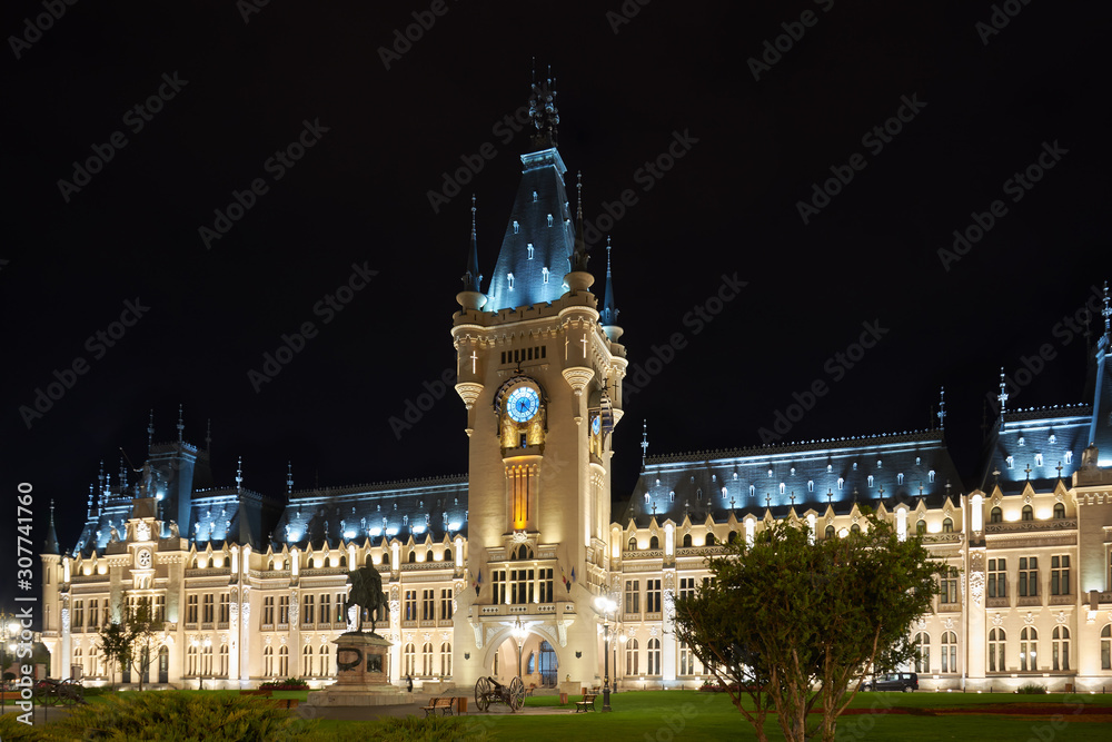 Clock tower of the Palace of Culture in Iasi, Romania. Evening illumination of the palace, cityscape. The building combines several architectural styles: neo-Gothic, romantic and neo-baroque.