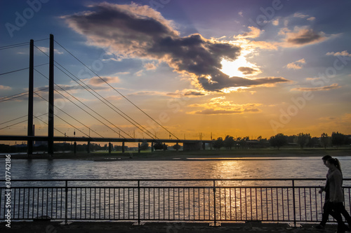 Dusseldorf  Germany - Cloud Formation in Shape of Arm Holding Setting Sun over the Rhine River and Bridge in Dusseldorf