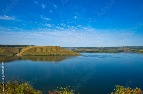summer time landscape photography of hill land view to horizon shore line district of lake peaceful waters 