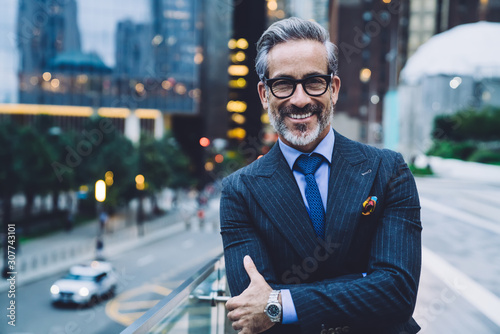 Photography Smiling mature business man with arms crossed on evening New York street