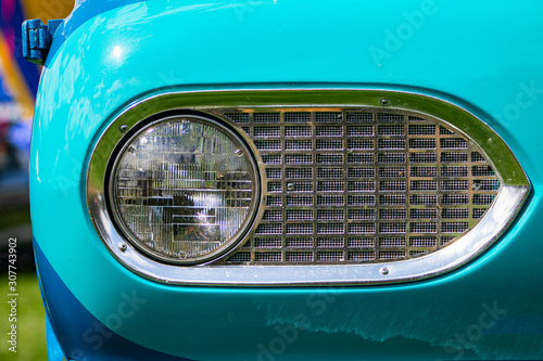 Turquoise blue old classic antique American car half front, left side, close up on glass headlight with metallic chrome frame © Valmedia