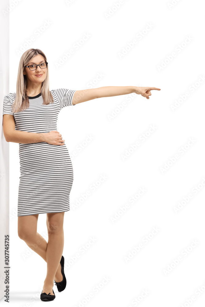 Young woman leaning on a wall and pointing to the side Young woman leaning on a wall and pointing to the side
