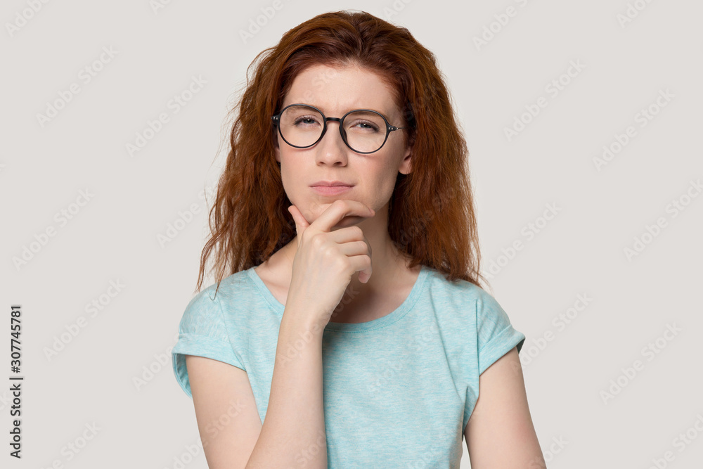 Head shot portrait of thoughtful millennial red-haired woman.