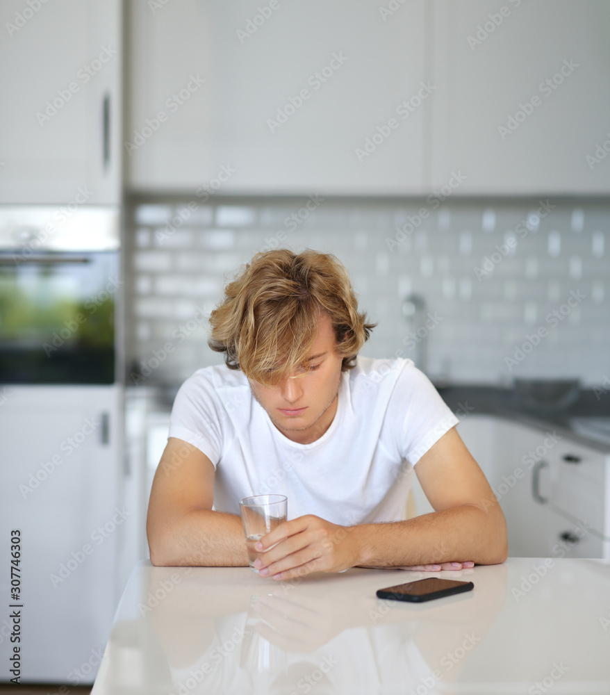 Teenage boy typing text message.Sitting in the kitchen.Using smart phone Teenage boy typing text message.Sitting in the kitchen.Using smart phone