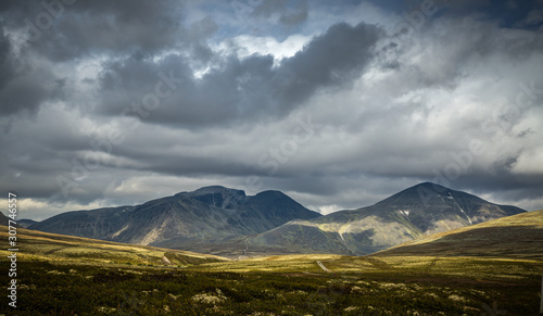 Autumn in Rondane National Park, mountain range and dark, cloudy sky, Norway.