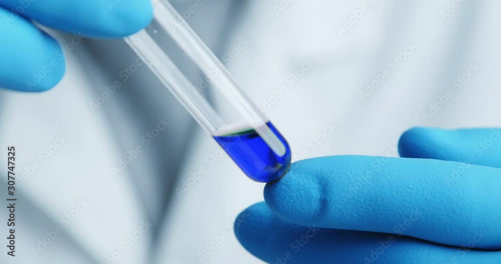 Close-up shot with hitting laboratory equipment. Blue liquid falling pipette in glass test tube. Close-up shot with hitting laboratory equipment. Blue liquid falling pipette in glass test tube.