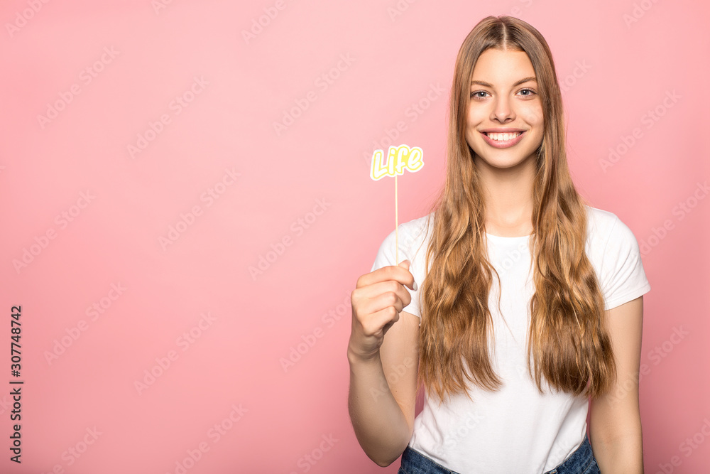 woman holding life lettering on stick isolated on pink woman holding life lettering on stick isolated on pink