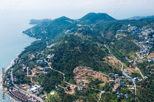 Aerial view of green mountain hills with built-up villas luxury for seasonal rent, housing surrounded by palm trees on an island in Samui, Thailand