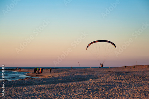 Rowy/Poland - June, 2019: Man flying on the paraglider over the beach in the evening