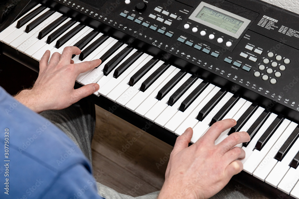hands of a pianist man playing a synthesizer in a bright home studio, top view hands of a pianist man playing a synthesizer in a bright home studio, top view