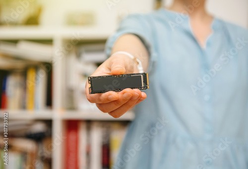 Woman hands holding new NVME PCIE SSD hard drive disk with high read and write speed lightflare sunlight photo