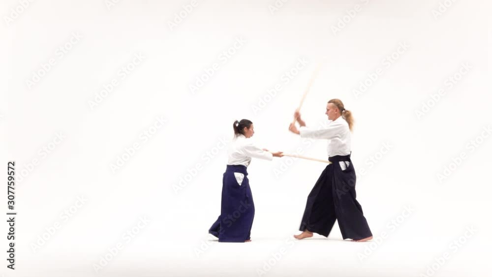Man and woman practicing aikido using bokken. Isolated on white. Slow motion. Man and woman practicing aikido using bokken. Isolated on white. Slow motion.