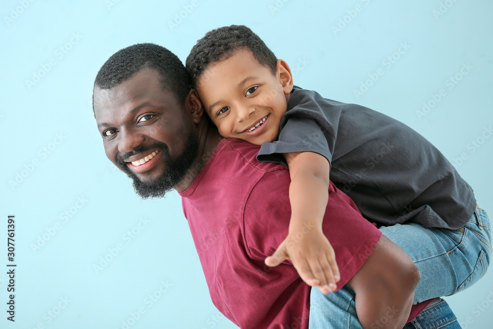 Portrait of African-American man with his little son on color background Portrait of African-American man with his little son on color background