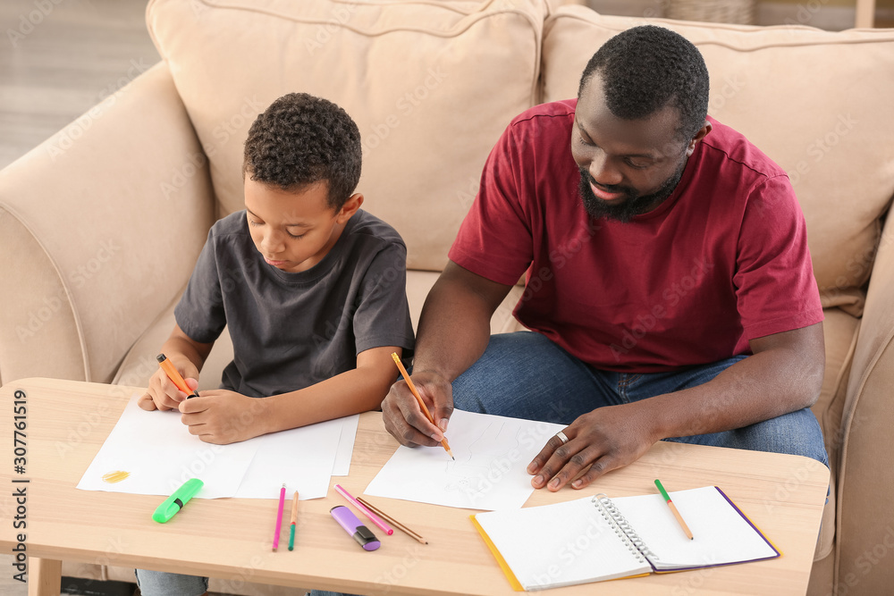 Portrait of African-American man and his little son drawing at home Portrait of African-American man and his little son drawing at home