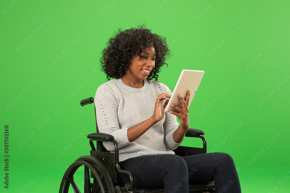 Happy disabled black woman using tablet on greenscreen - obrazy, fototapety, plakaty 