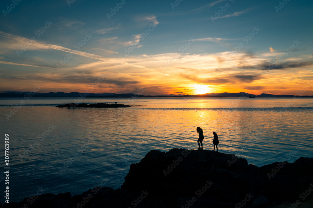 Kids exploring rocky coast at sunset