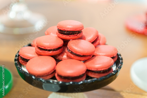 Red Macarons. Several strawberries-flavored pink macarons on a white and black ceramic tray. Children's party decoration with the detective theme. Selective focus with blur. photo