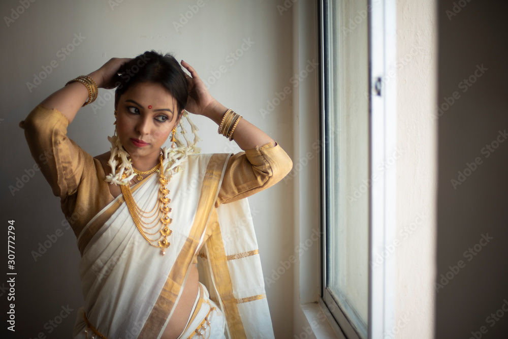 Portrait of an young and attractive Indian woman in white traditional ...