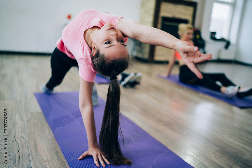 Fototapeta premium Athletic female doing backbend in gym