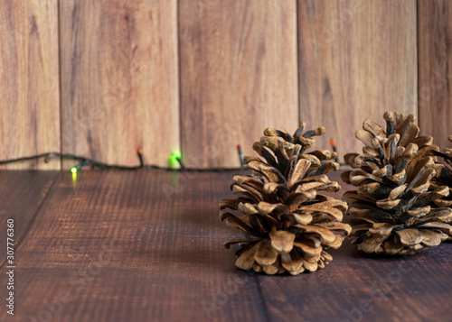 Christmas composition. Pine cones on a rustic vintage wooden background with a garland. Flat lay, top view, copy space