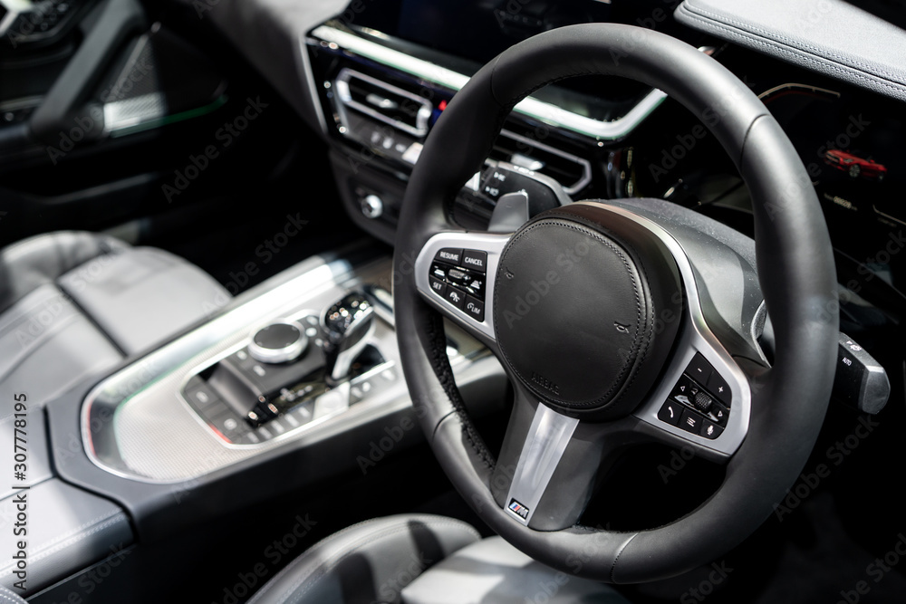 Dark luxury car Interior - steering wheel, shift lever and dashboard. Car interior luxury. Beige comfortable seats, steering wheel, dashboard, climate control, speedometer, display, light wood panels