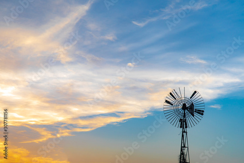 Old wind turbine with blue sunset sky and clouds at evening or twilight time.