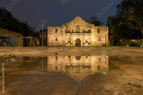 Murais de parede Low Angle View of the San Antonio Alamo Reflected on Rain Puddle
