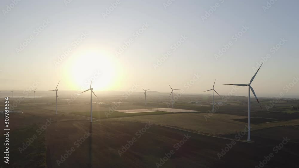 Wind turbine farm on beautiful purple morning landscape. Renewable energy production for green ecological world. Aerial view of wind mills farm park Wind turbine farm on beautiful purple morning landscape. Renewable energy production for green ecological world. Aerial view of wind mills farm park