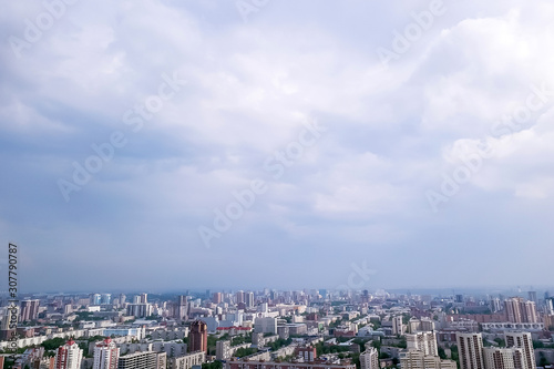 Aerial view of the landscape in a big city with high houses and skyscrapers in the center of Novosibirsk under a cloudy sky with fog and haze on a summer cloudy day.